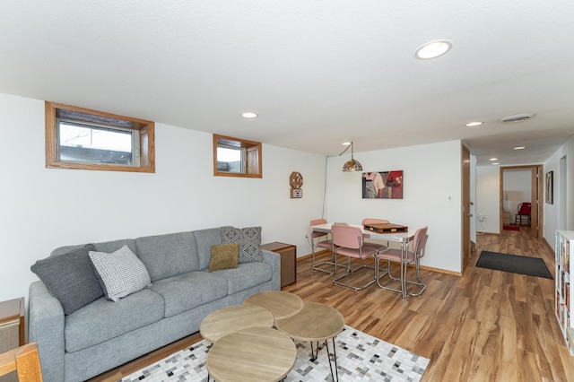 living area featuring light wood-style floors, baseboards, visible vents, and recessed lighting