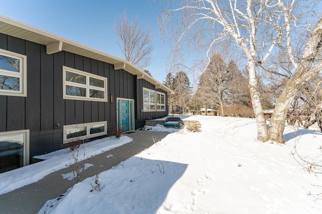 snow covered property with board and batten siding