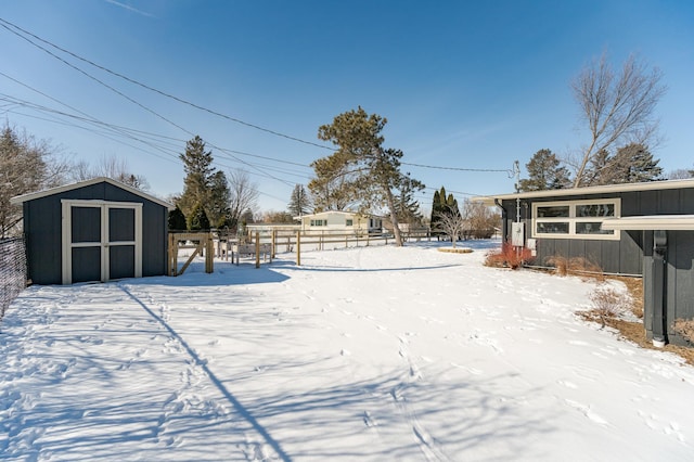 yard covered in snow featuring a storage shed, an outdoor structure, and fence