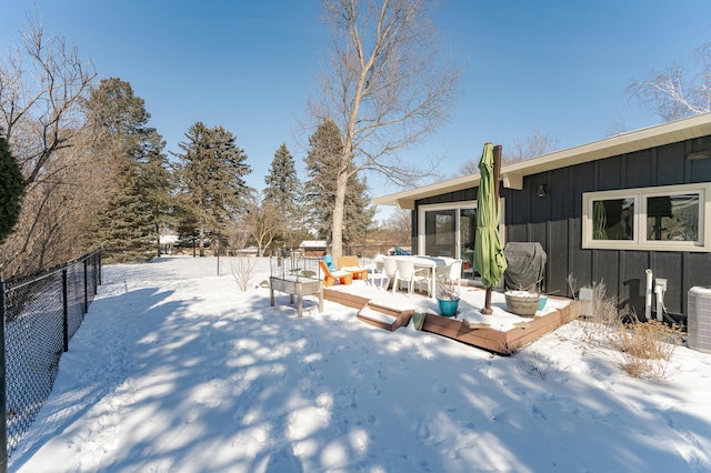 yard covered in snow with outdoor dining area, fence, and a deck