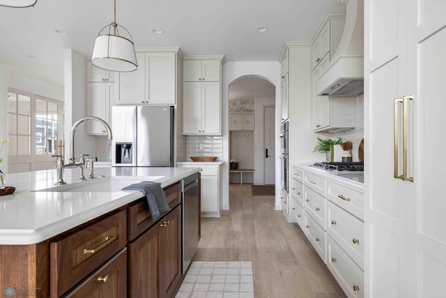 3254 Timber Creek Cir S, Fargo, ND 58104 - kitchen featuring appliances with stainless steel finishes, custom range hood, arched walkways, light countertops, and tasteful backsplash
