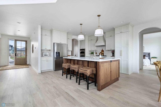 3254 Timber Creek Cir S, Fargo, ND 58104 - kitchen featuring stainless steel appliances, arched walkways, custom exhaust hood, light wood-style floors, and light countertops