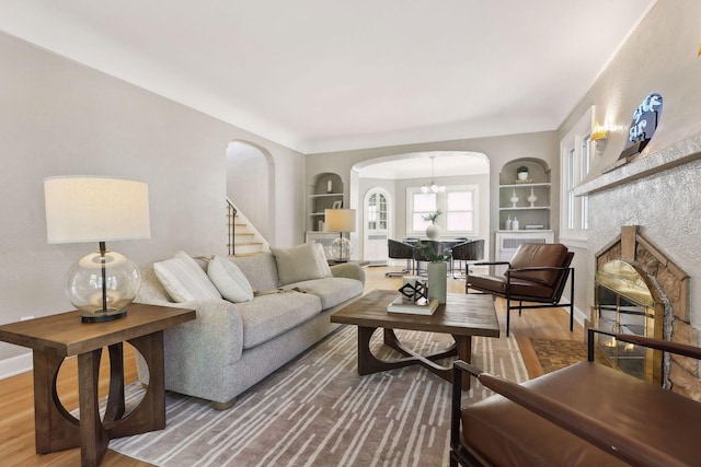 living area with built in shelves, arched walkways, and wood finished floors