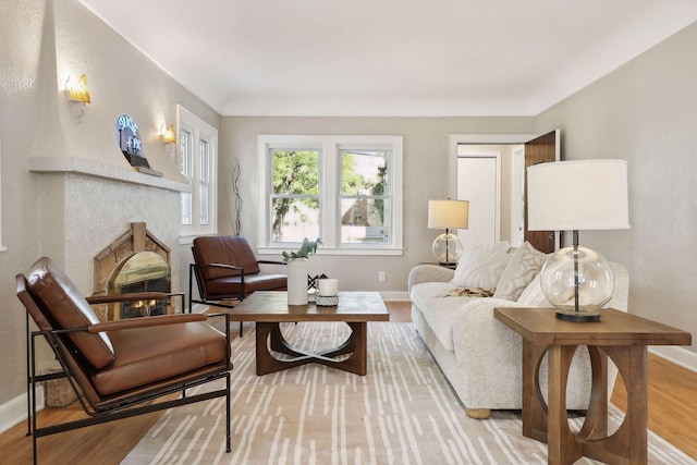 living area with a fireplace, baseboards, and wood finished floors