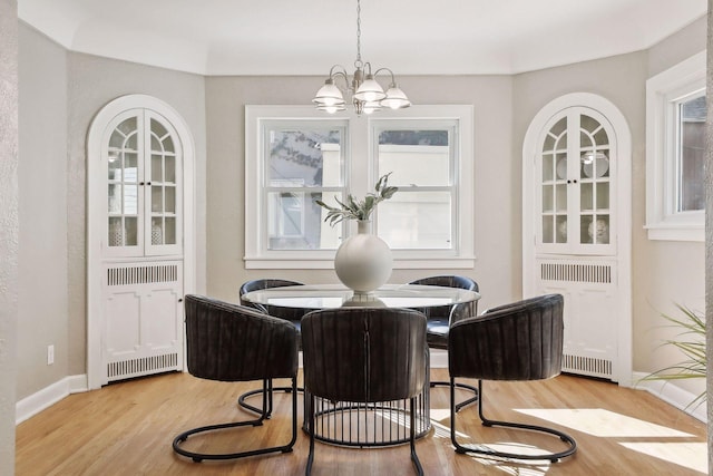 dining space featuring baseboards, radiator heating unit, an inviting chandelier, and light wood-style floors