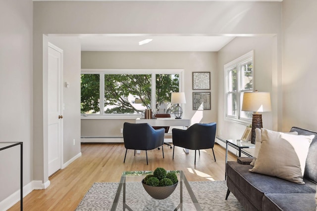 sitting room featuring light wood-style floors, baseboards, and a baseboard heating unit