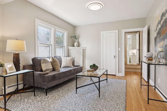 living area with light wood-type flooring, baseboard heating, and baseboards