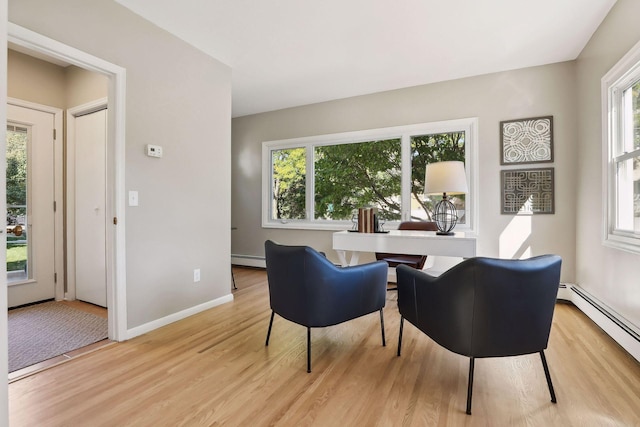 sitting room with a wealth of natural light, baseboard heating, and light wood-style flooring