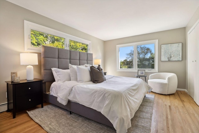 bedroom featuring light wood finished floors, multiple windows, and baseboards