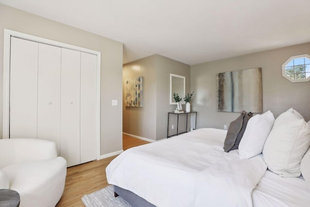 bedroom featuring light wood-type flooring, baseboards, and a closet