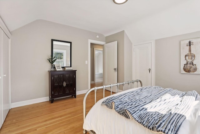 bedroom with lofted ceiling, a closet, wood finished floors, and baseboards