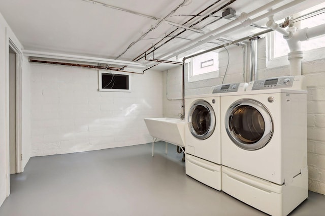 washroom featuring concrete block wall, laundry area, a sink, and independent washer and dryer