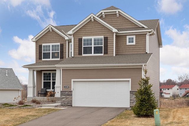 craftsman-style home featuring roof with shingles, driveway, stone siding, a garage, and covered porch