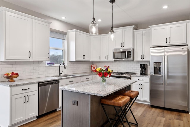 kitchen with white cabinets, a sink, appliances with stainless steel finishes, recessed lighting, and a kitchen island