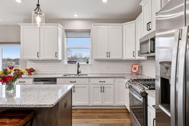 kitchen with recessed lighting, backsplash, white cabinets, stainless steel appliances, and a sink