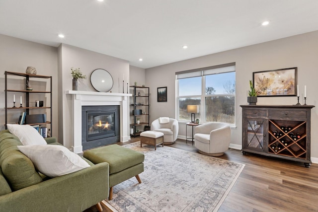 living room featuring wood finished floors, baseboards, a glass covered fireplace, and recessed lighting