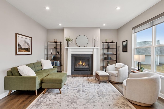 living area with baseboards, recessed lighting, a fireplace with flush hearth, and dark wood-style floors