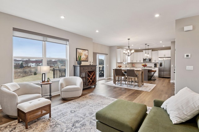 living area with recessed lighting, a notable chandelier, and wood finished floors