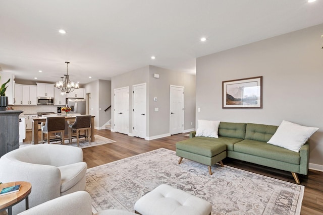 living room featuring dark wood-style flooring, baseboards, recessed lighting, and an inviting chandelier