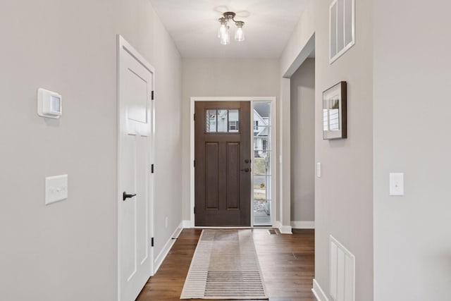 foyer entrance featuring dark wood-style flooring, visible vents, and baseboards