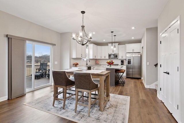 dining space with wood finished floors, a notable chandelier, baseboards, and recessed lighting