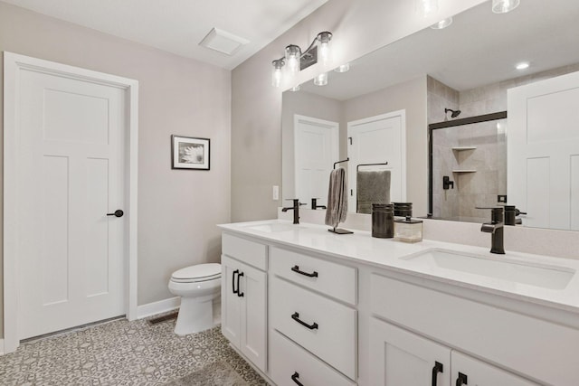 bathroom featuring a shower stall, double vanity, a sink, and toilet