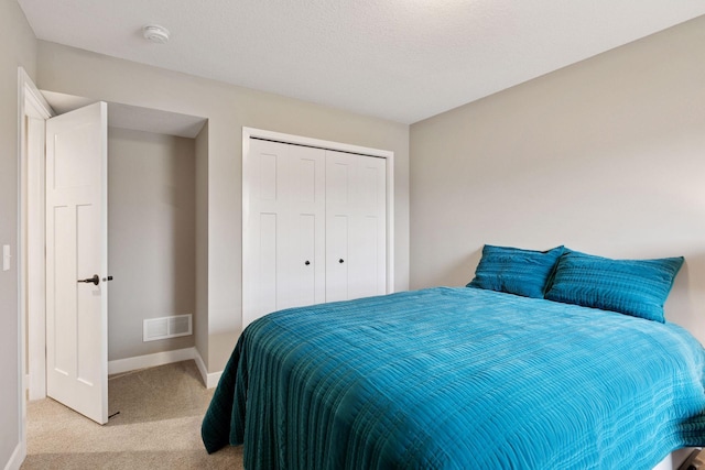carpeted bedroom with a closet, baseboards, and visible vents