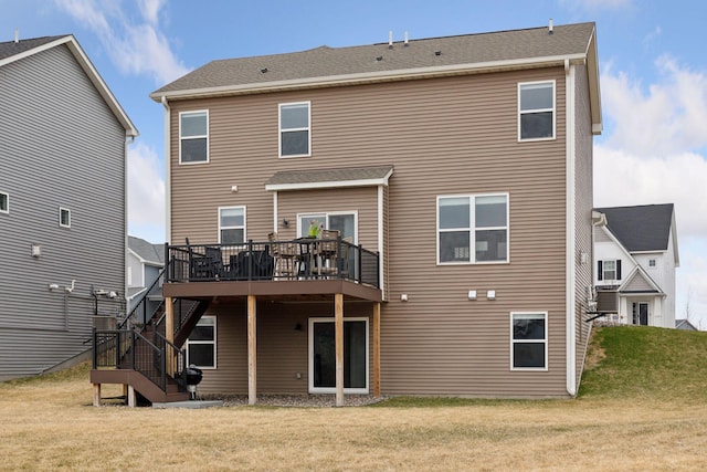 rear view of property featuring a deck, a lawn, and stairs