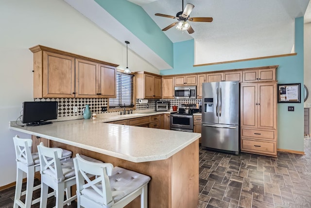 kitchen with a peninsula, appliances with stainless steel finishes, light countertops, and decorative backsplash