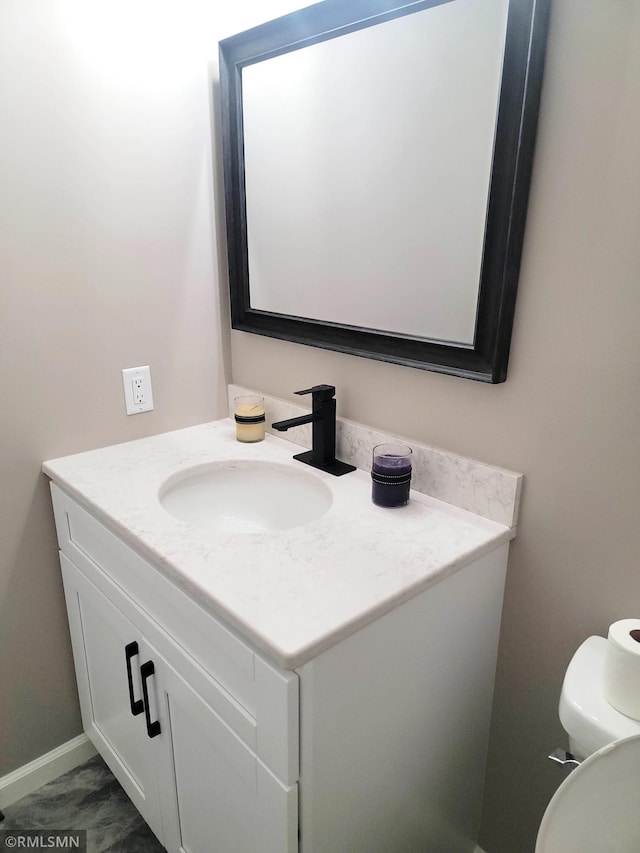 bathroom with baseboards, vanity, and toilet