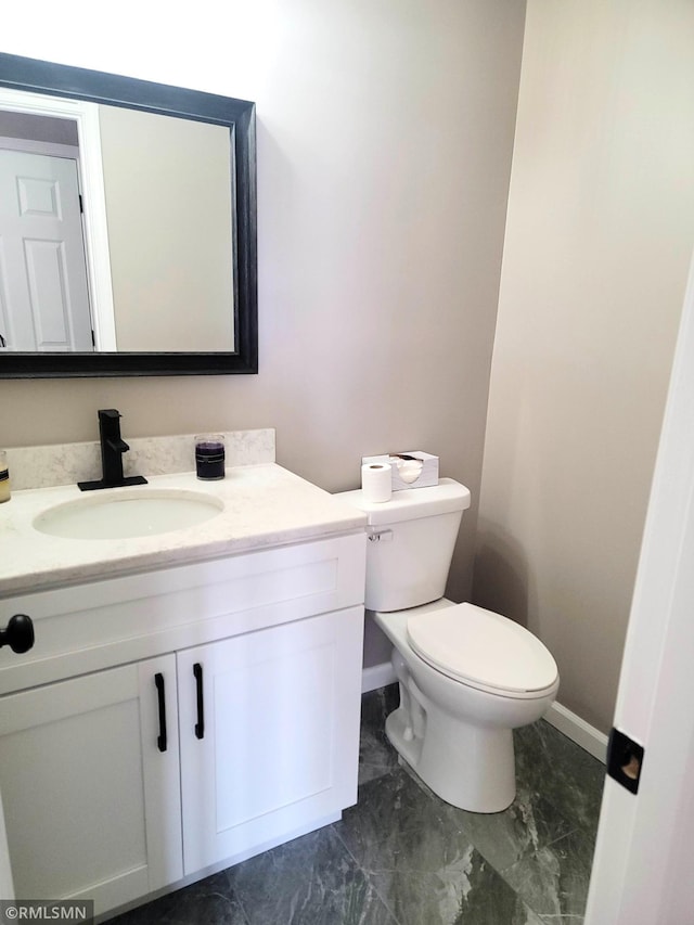 bathroom featuring marble finish floor, baseboards, vanity, and toilet