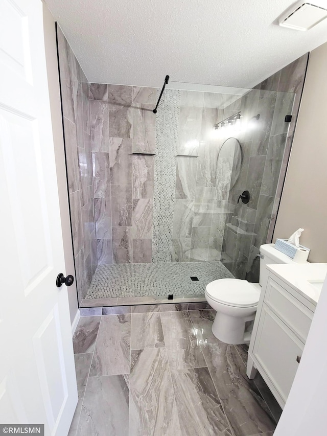 full bathroom featuring visible vents, toilet, a textured ceiling, vanity, and walk in shower