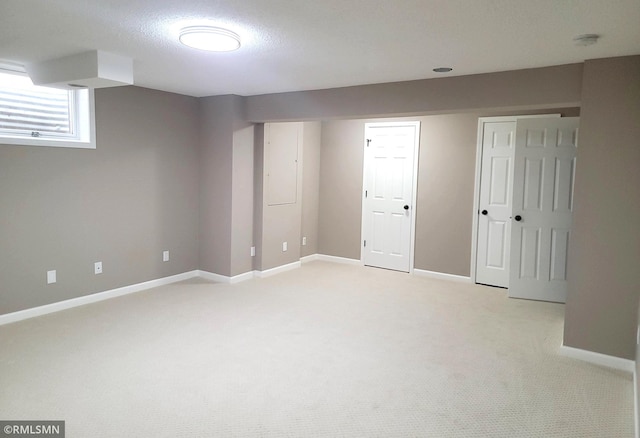 interior space featuring light colored carpet, a textured ceiling, and baseboards