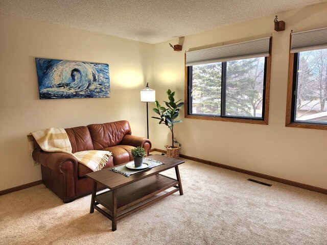 living room featuring light carpet, a textured ceiling, visible vents, and baseboards