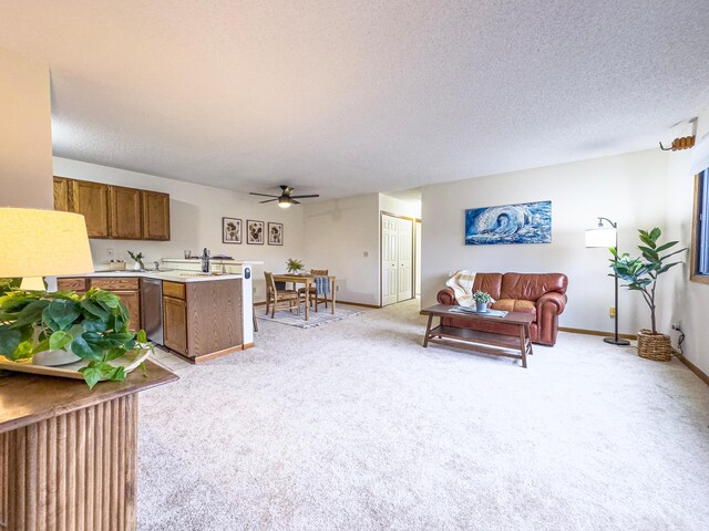 living room featuring light carpet, ceiling fan, a textured ceiling, and baseboards