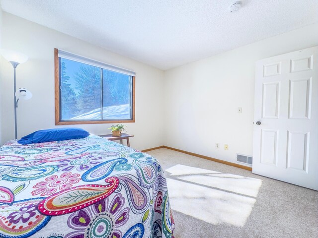 bedroom with carpet floors, baseboards, visible vents, and a textured ceiling