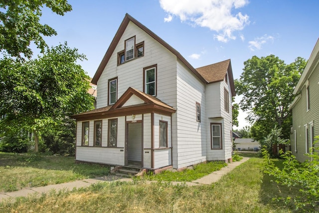 view of front of house featuring a shingled roof and a front yard