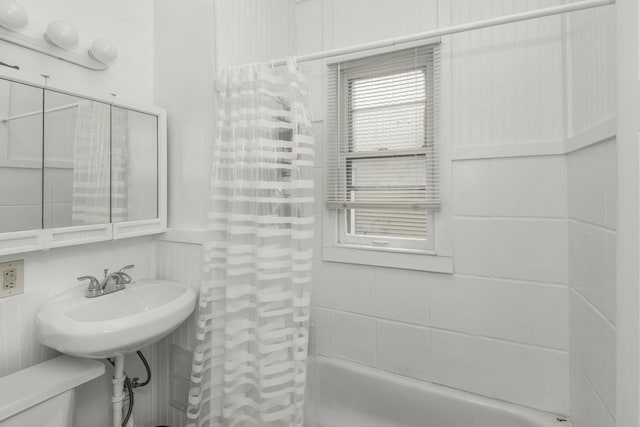 full bath with a wainscoted wall, shower / bath combo, and a sink