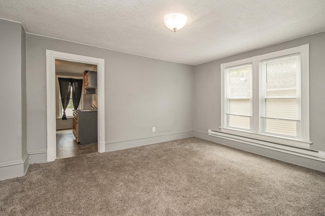 unfurnished room featuring a textured ceiling, a sink, baseboards, baseboard heating, and dark carpet