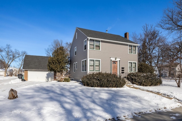 colonial home with a garage, roof with shingles, an outdoor structure, and a chimney