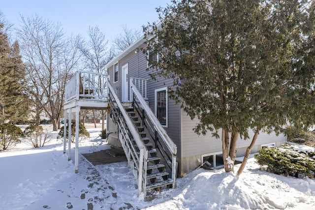 view of snowy exterior with stairs and a wooden deck