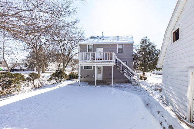 snow covered property featuring a deck and stairs