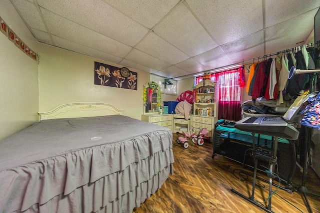 bedroom featuring a drop ceiling and wood finished floors