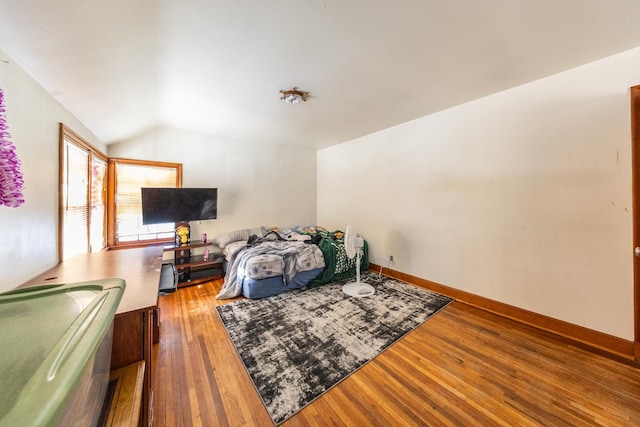 living room featuring lofted ceiling, baseboards, and wood finished floors