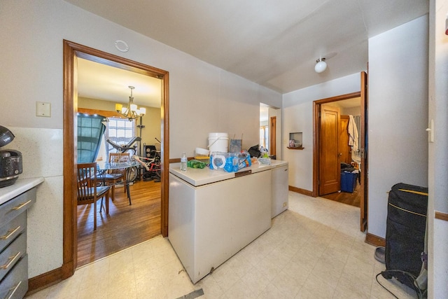 kitchen with light countertops, a notable chandelier, light floors, and white refrigerator