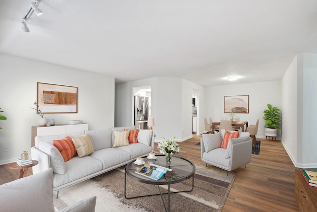 living area featuring dark wood-type flooring, track lighting, and baseboards