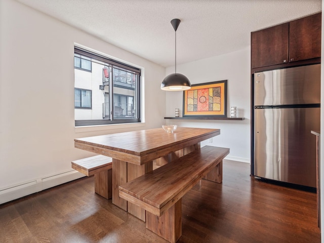 dining area featuring a textured ceiling, baseboards, baseboard heating, breakfast area, and dark wood finished floors