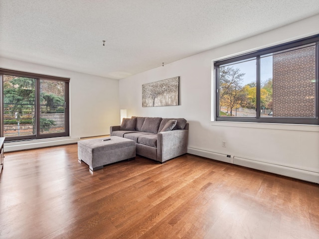 living area featuring a textured ceiling, a baseboard radiator, and wood finished floors