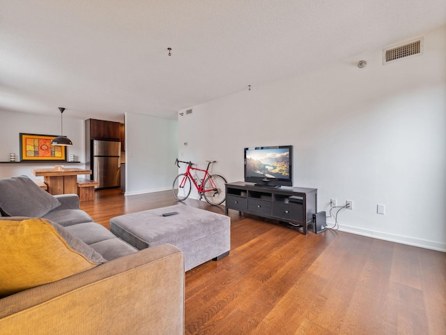 living area featuring baseboards, visible vents, and dark wood-style flooring