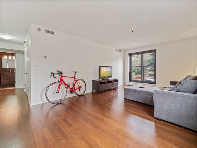 living area featuring wood finished floors, visible vents, and baseboards